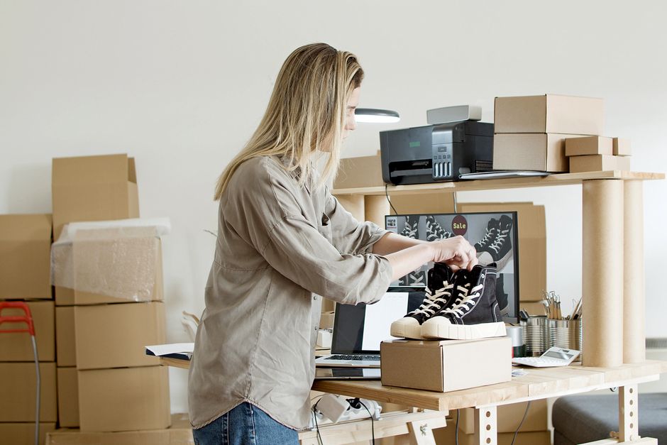 Mulher separando produtos em caixa em espaço de trabalho de e-commerce