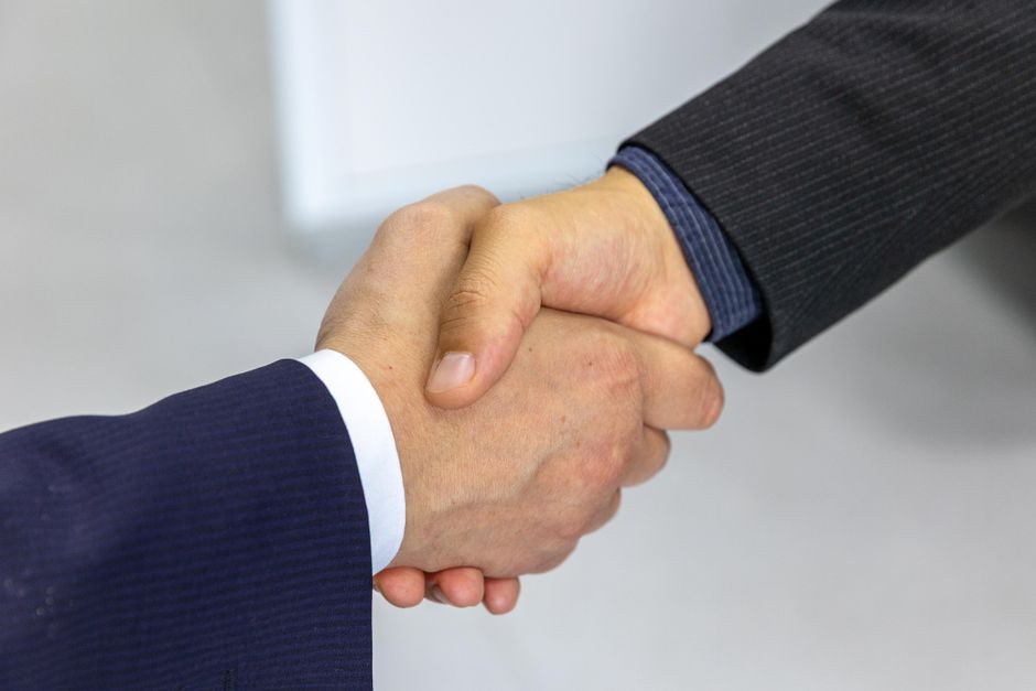 Aperto de mãos selando acordo comercial entre empresa de software e cliente