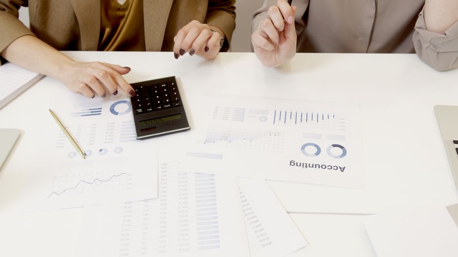 Duas profissionais analisando documentos financeiros com calculadora