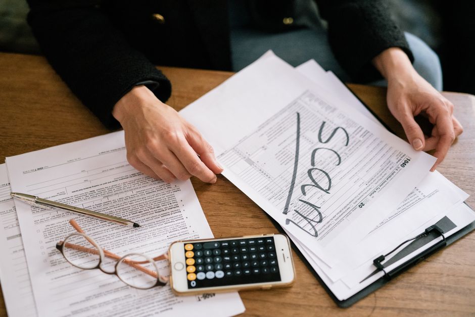 Mãos examinando formulário fiscal com calculadora e papéis na mesa